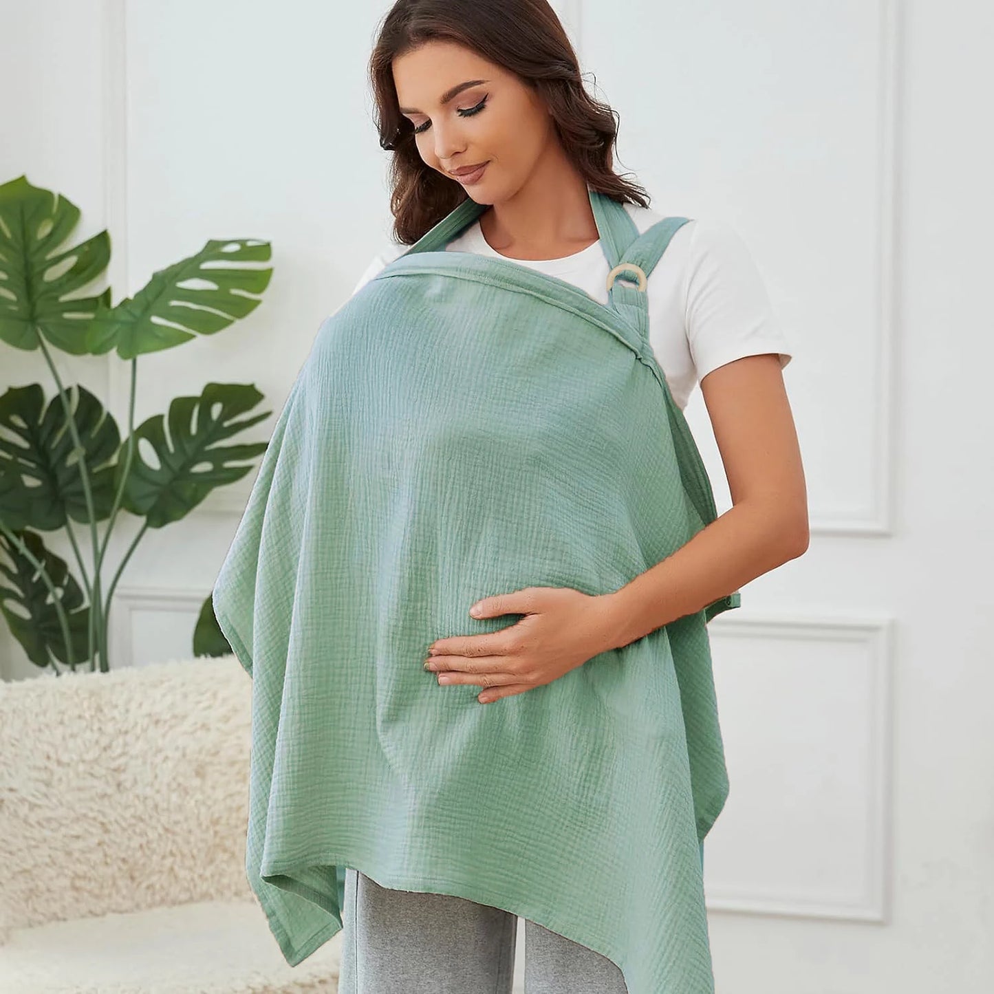Woman wearing a green baby carrier with a white background
