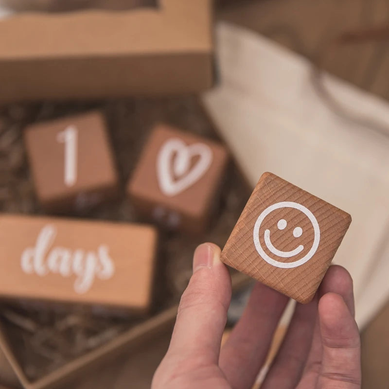 Wooden blocks with numbers and symbols held by a hand, with a blurred background
