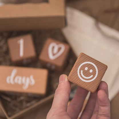 Wooden blocks with numbers and symbols held by a hand, with a blurred background