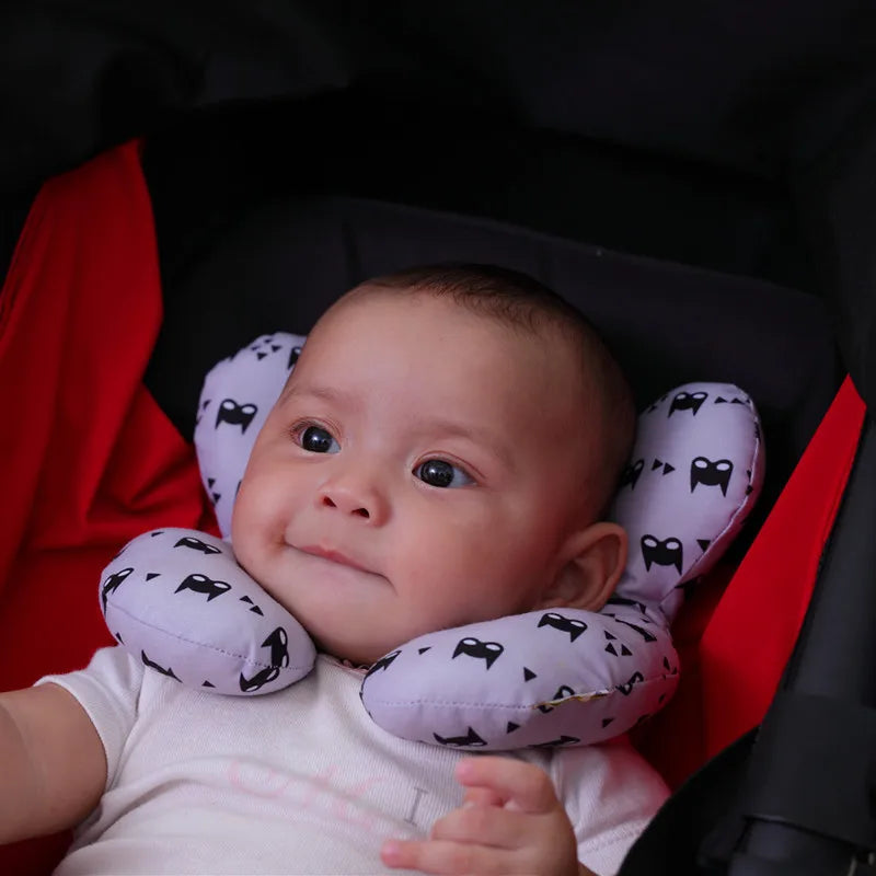 Baby wearing a purple neck pillow with black patterns in a car seat.