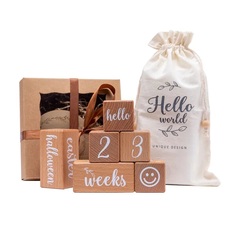 Wooden blocks with milestone text and a drawstring bag labeled 'Hello World' on a white background