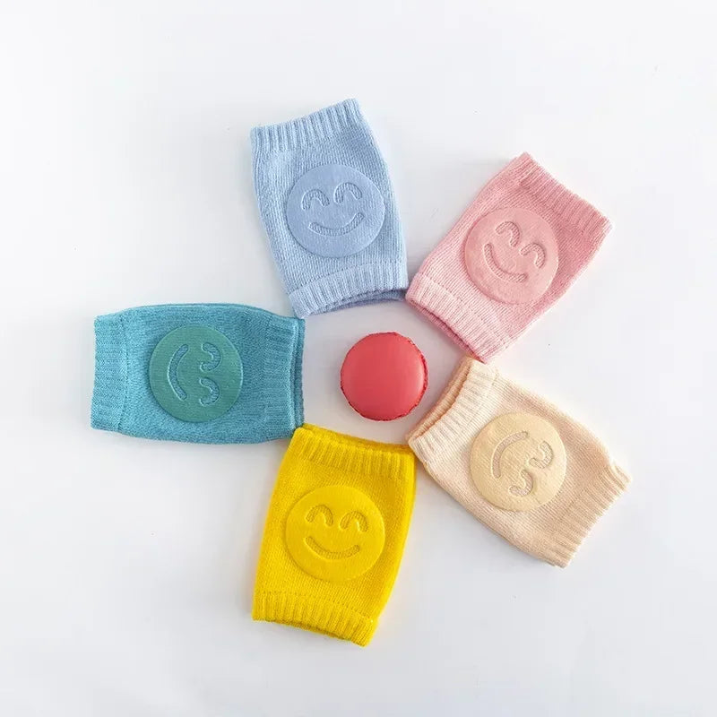 Five colorful baby leg warmers with smiley face designs on a white background