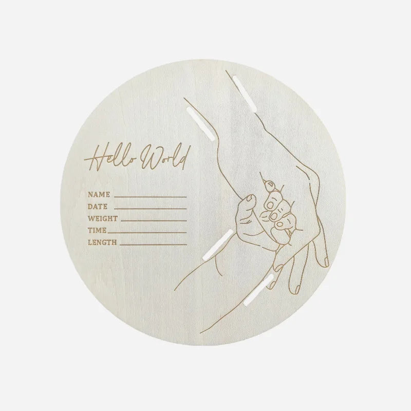 Round wooden product with engraved design of a hand holding a baby and text on a white background