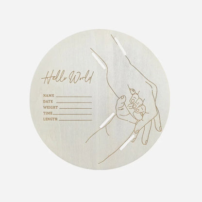 Round wooden product with engraved design of a hand holding a baby and text on a white background