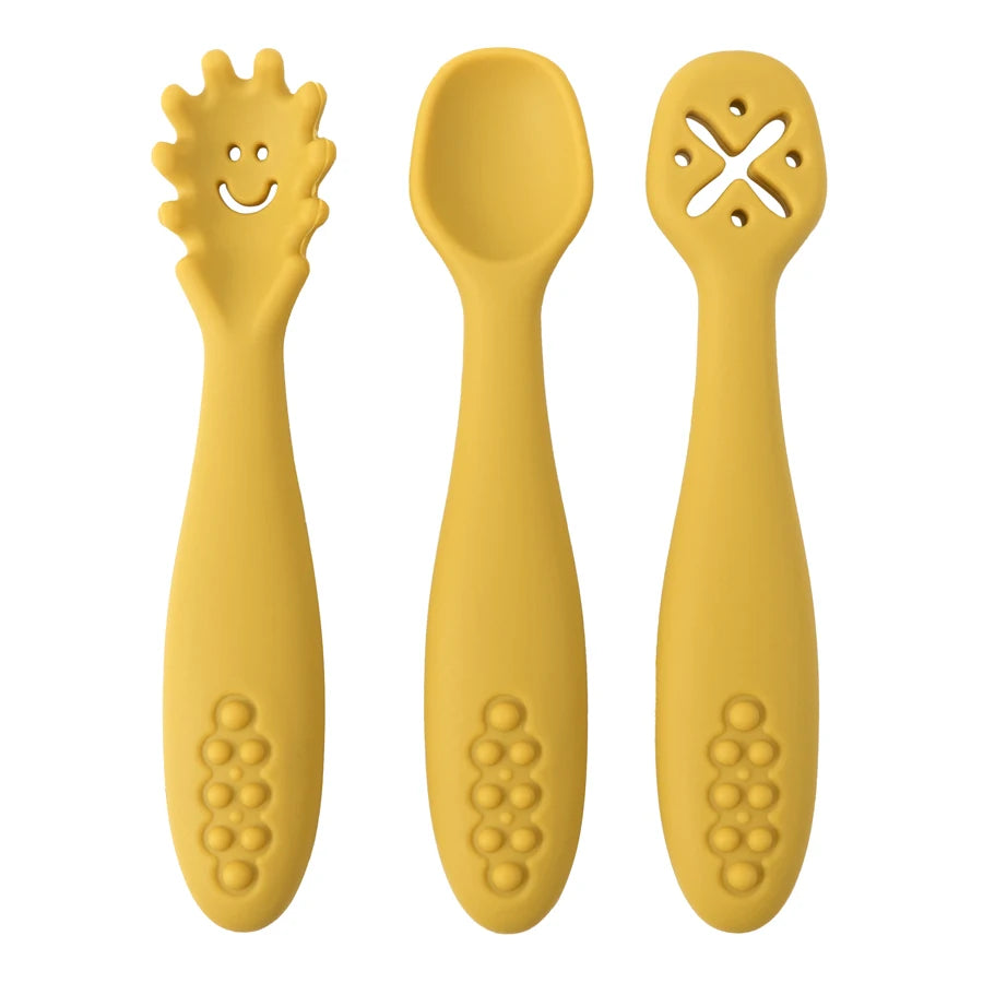 Three yellow baby utensils with different designs on a white background