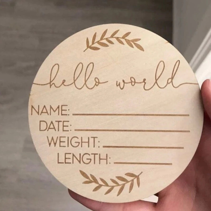 Round wooden card with engraved text 'hello world' and placeholders for name, date, weight, and length, held by a hand.