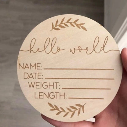 Round wooden card with engraved text 'hello world' and placeholders for name, date, weight, and length, held by a hand.