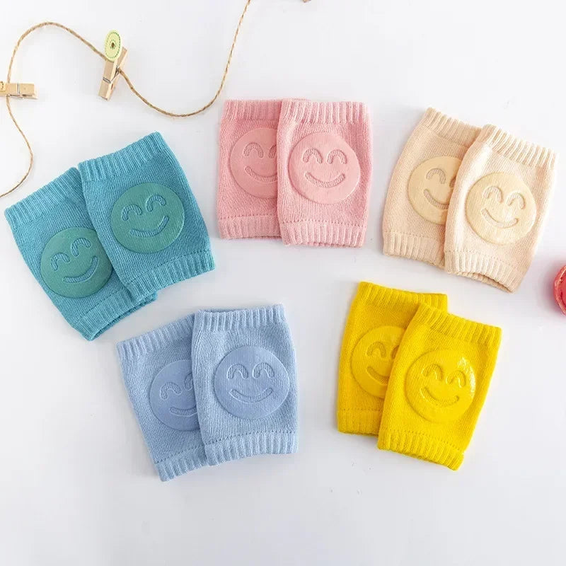 Colorful baby knee pads with smiley face designs on a white background