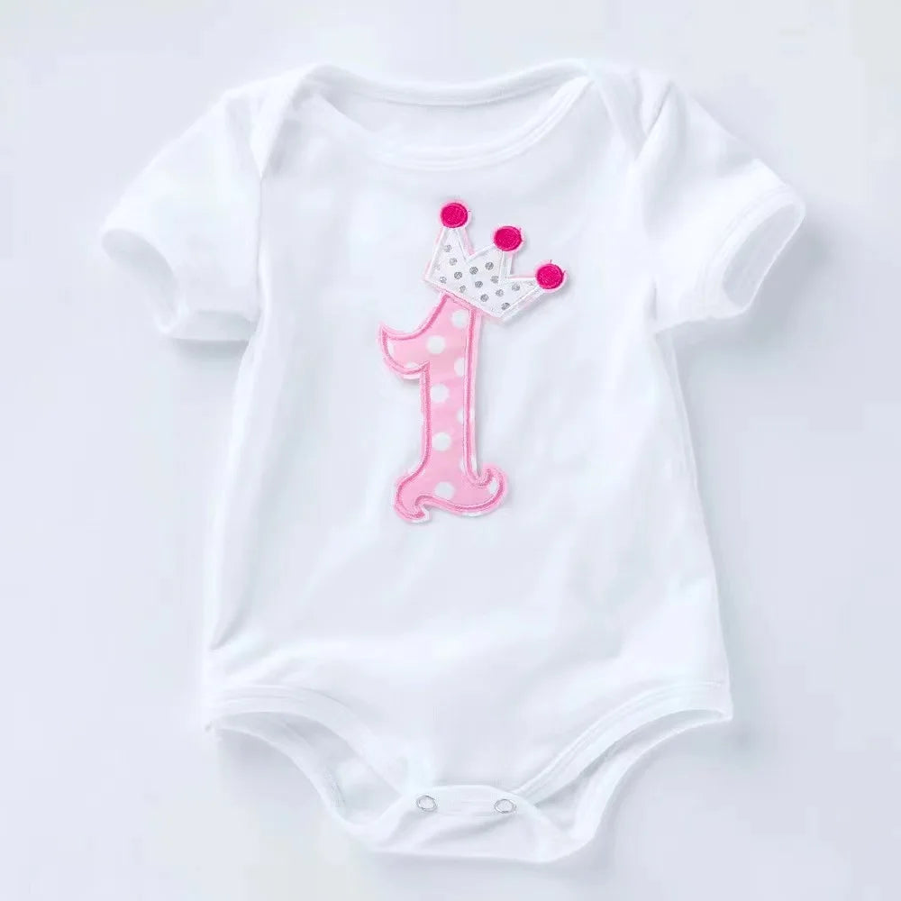 White baby onesie with pink number one and crown on a white background