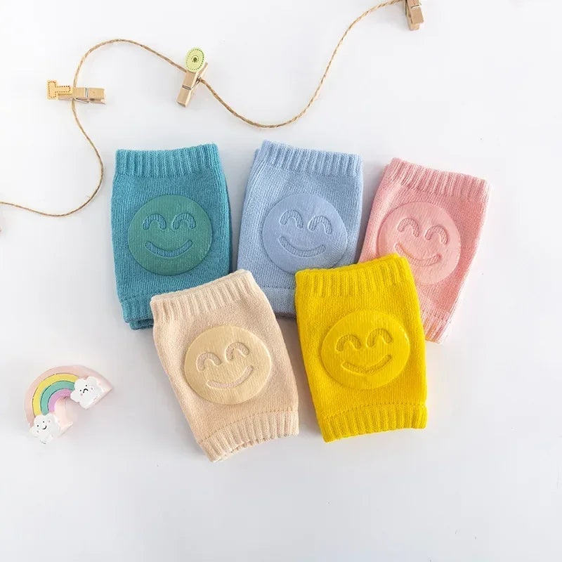 Five colorful baby leg warmers with smiley face designs on a white background.