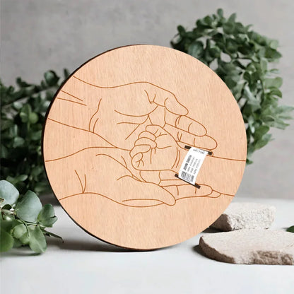 Wooden round cutting board with engraved hands design on a neutral background