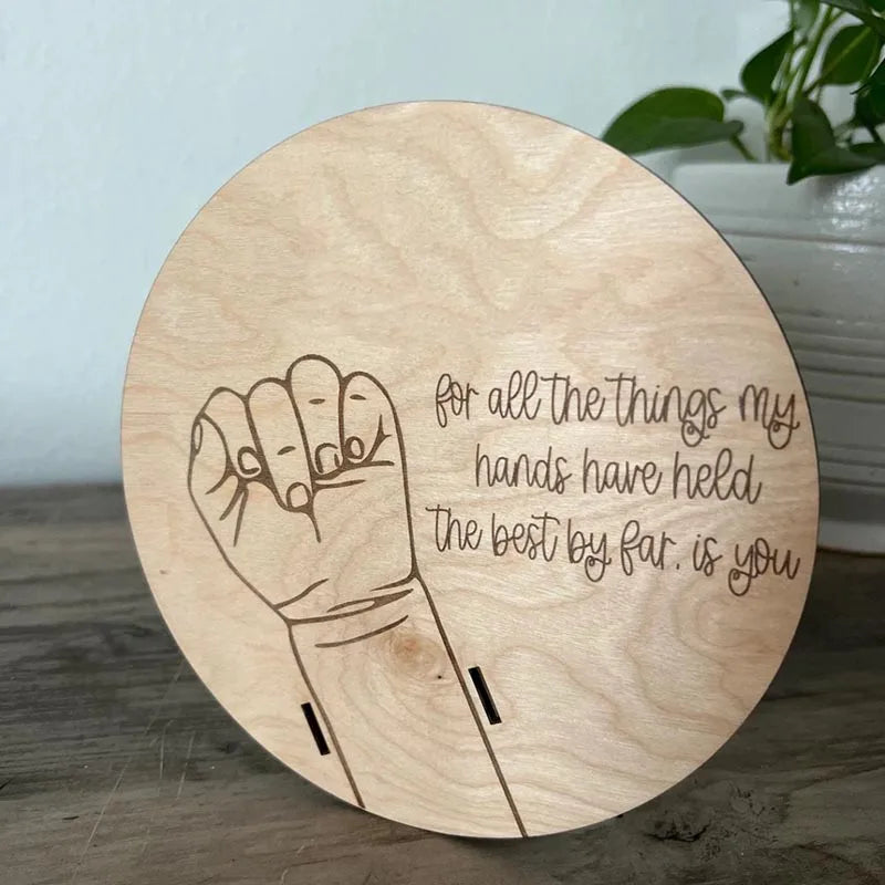 Wooden round sign with a raised fist illustration and engraved text on a wooden surface.