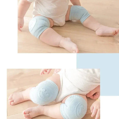 Baby wearing light blue knee pads on a wooden floor.