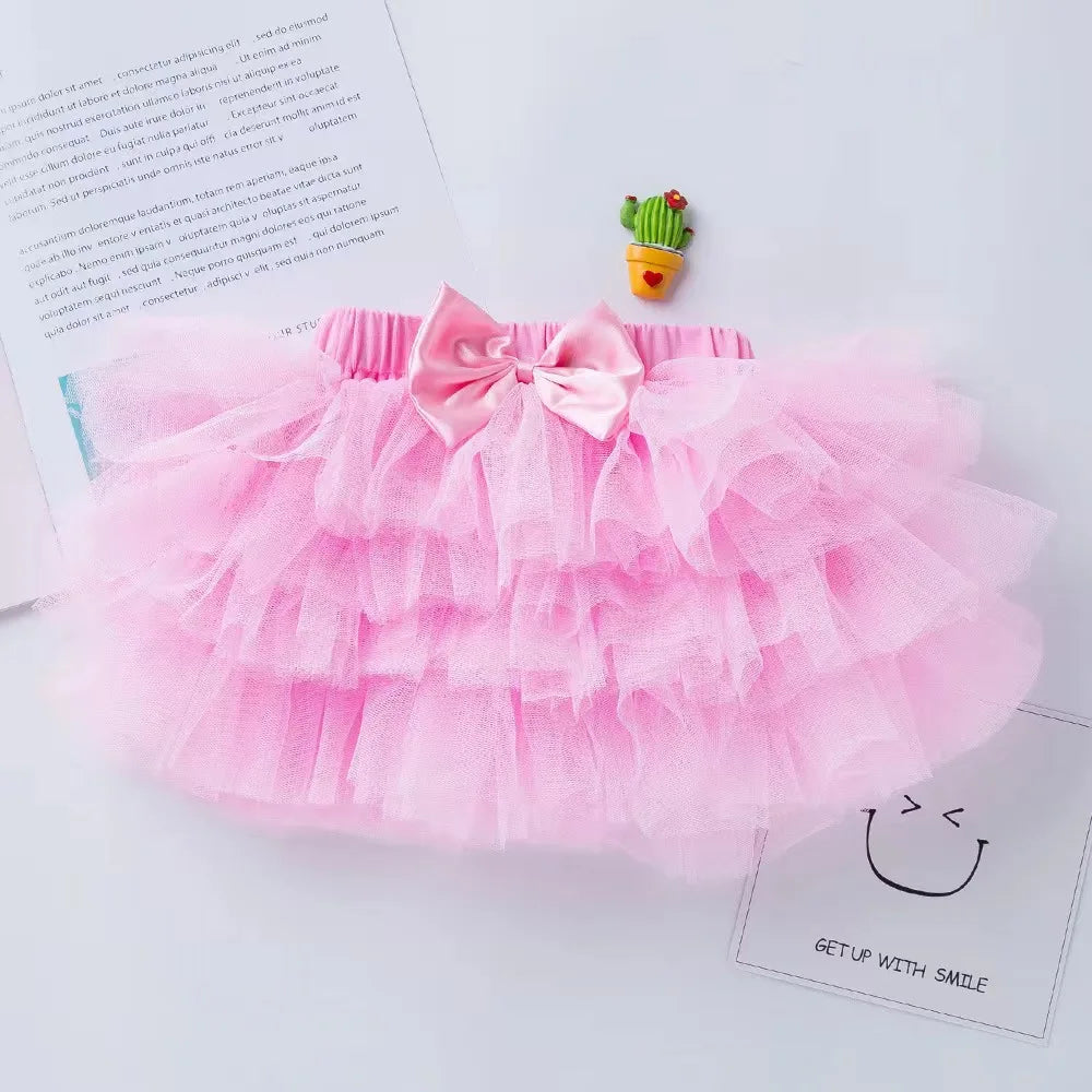 Pink tutu skirt with a bow on a white surface with a cactus decoration.