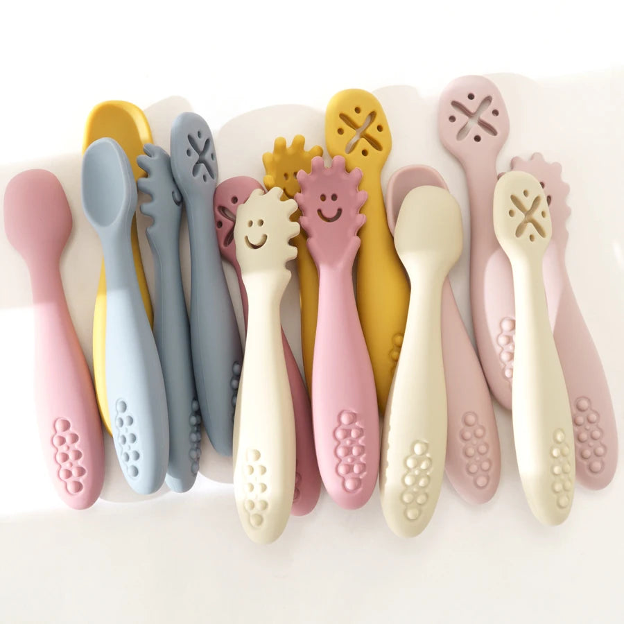 Set of colorful baby utensils with smiley faces on a white background