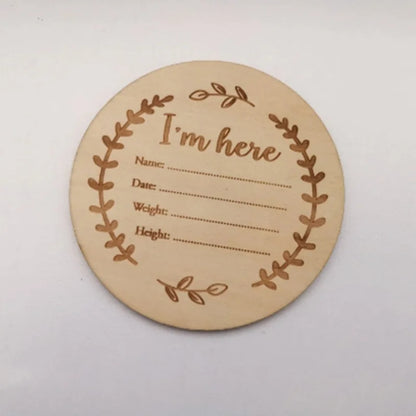 Round wooden card with engraved text and leaf design on a white background