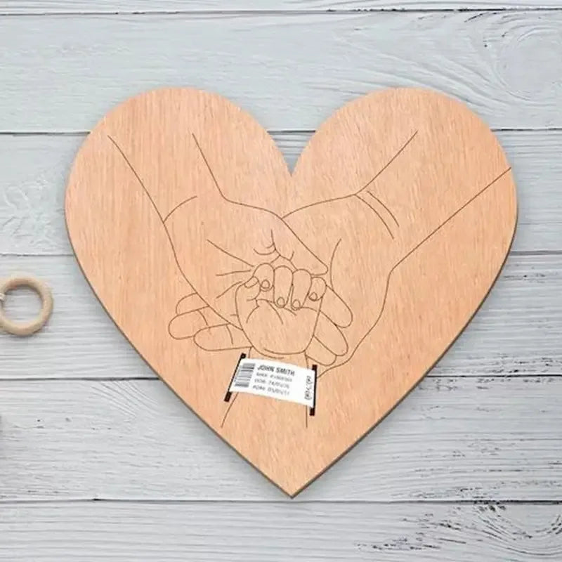 Wooden heart-shaped plaque with engraved hands holding a ring on a light wooden background
