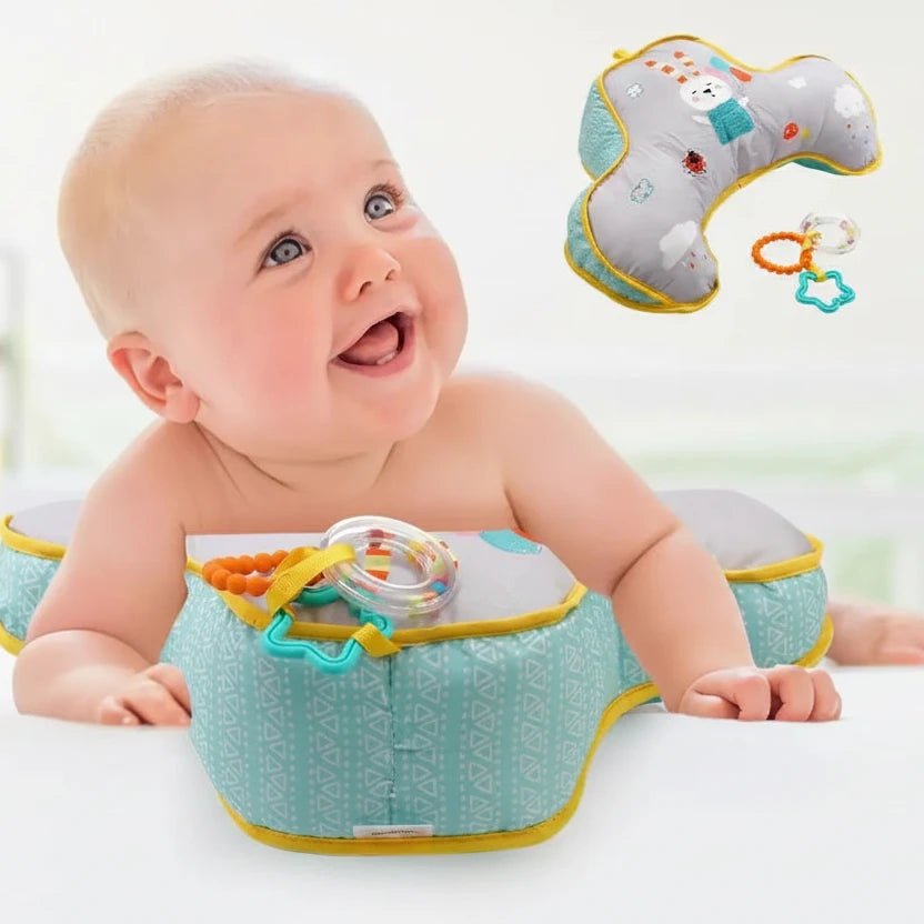 Baby using a tummy time pillow with toys attached, on a white background