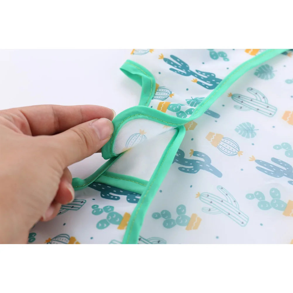Hand holding a green hanger over a fabric with cactus pattern